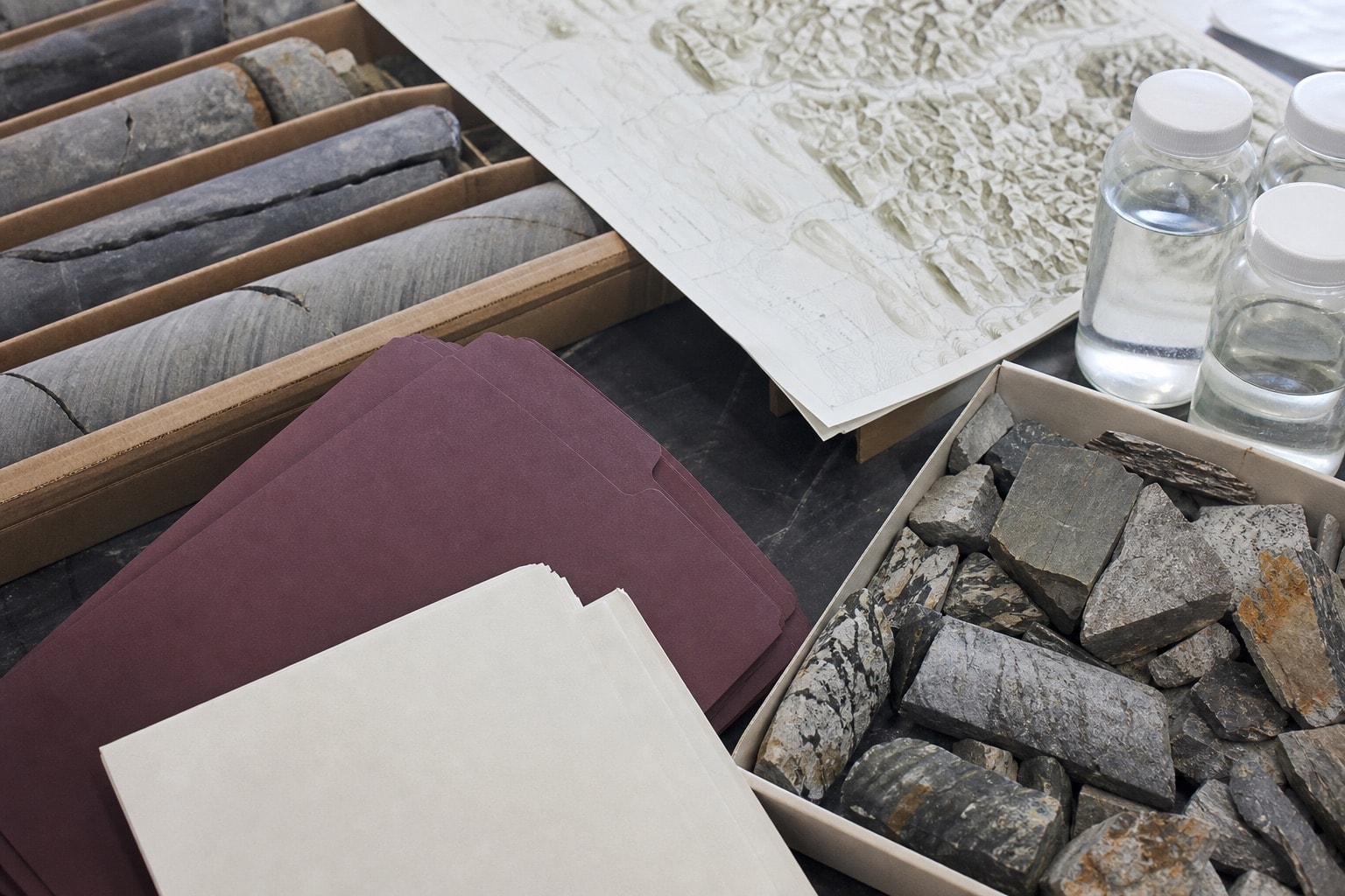 Geological samples, maps, and anonymous permit files on a research bench